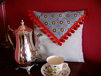 Image of a French Country pillow with red pom pom trim.